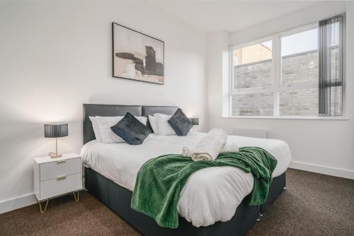 a bedroom with a bed with a green blanket on it at Premium 2 Bed Apartment - Free Parking - Town Centre - Station in Luton