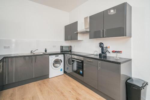 a kitchen with gray cabinets and a washer and dryer at Premium 2 Bed Apartment - Free Parking - Town Centre - Station in Luton