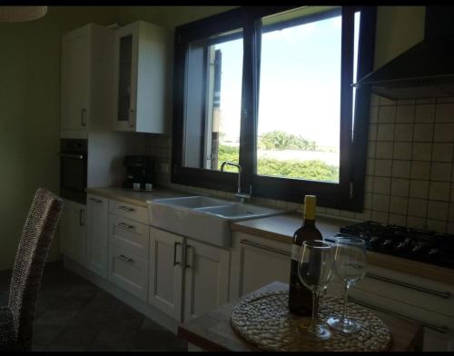 a kitchen with a sink and a bottle of wine on a table at Resort Villa Brucoli Gardens of Syracuse in Brucoli