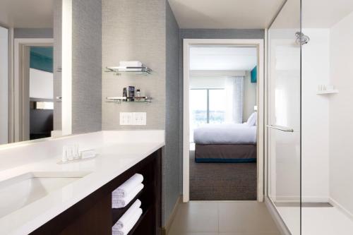 Residence Inn by Marriott Indianapolis Plainfield في بلينفيلد: حمام مع حوض وغرفة نوم