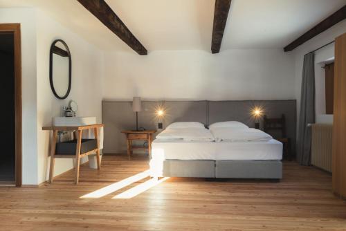 Schlafzimmer mit einem Bett, einem Tisch und einem Spiegel in der Unterkunft Ansitz Heufler in Oberrasen