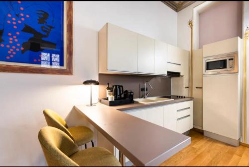 uma cozinha com armários brancos e uma mesa e cadeiras em Dimora Novecento [PORTA NUOVA-CENTRO] em Turim