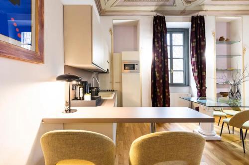 uma cozinha com mesa e cadeiras num quarto em Dimora Novecento [PORTA NUOVA-CENTRO] em Turim