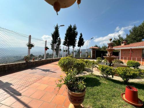 eine Terrasse mit Pflanzen und einem Zaun und einem Haus in der Unterkunft Finca Villa Maria - Cabaña in Ráquira
