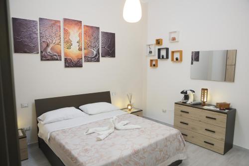 una camera da letto con un letto con tre dipinti sul muro di Ripa Alta Room's a Cerignola