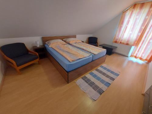 a small bedroom with a bed and a chair at Krisztina-Rózsa ház in Balatonföldvár