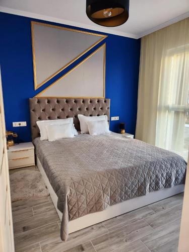 1 dormitorio con 1 cama grande y paredes azules en Apartament ASB Oradea, en Oradea