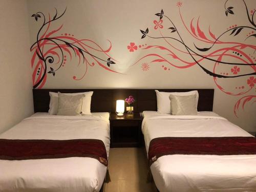 two beds in a room with a painting on the wall at NAKA GUEST HOUSE in Ban Ko Kwang