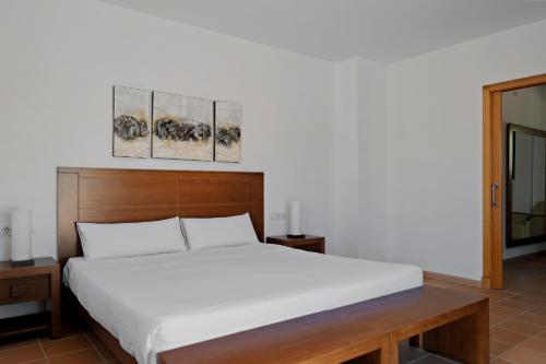 um quarto com uma cama branca e duas pinturas na parede em Prinsotel Villas Cala Galdana em Cala Galdana