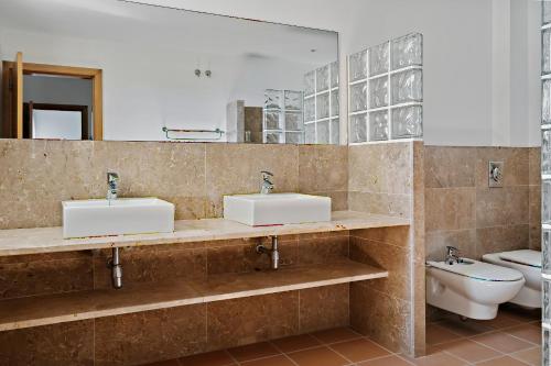 a bathroom with two sinks and a toilet at Prinsotel Villas Cala Galdana in Cala Galdana