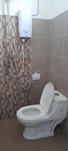 a bathroom with a white toilet and a shower at Kayangan Apartment in Kangar