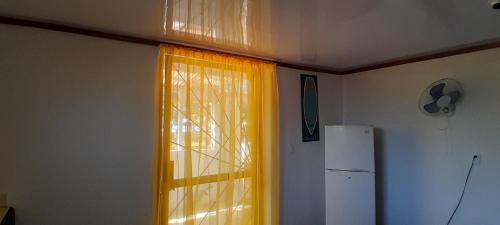 eine Küche mit einem Fenster mit gelben Vorhängen und einem Kühlschrank in der Unterkunft ALOHA BEACH FROM HOUSE in Parrita