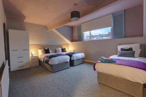 um quarto com 2 camas e uma janela em Stylish 3 Bed Apartment, Abbeydale Rd - Sleeps 8, FREE Parking & Netflix em Sheffield