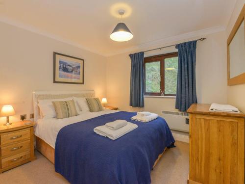a bedroom with a bed with blue sheets and a window at 19 Burgh Island Causeway in Kingsbridge