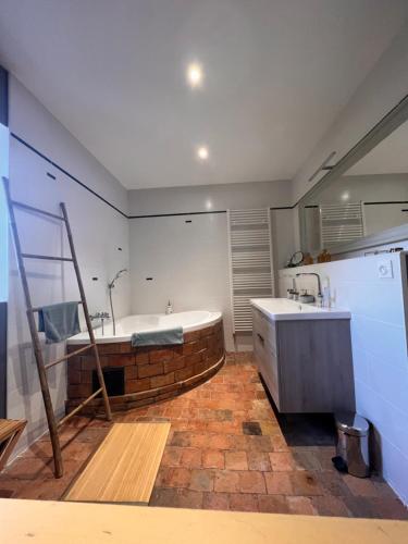 a bathroom with a brick tub and a sink at La maison d'Hélios in Alençon