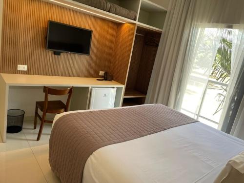 a bedroom with a bed and a desk and a television at Hotel Jardim in Jardim