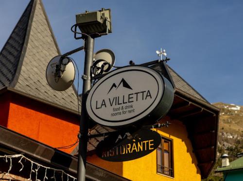 a sign on a pole in front of a building at La Villetta Food & Drink Rooms for Rent - No Reception - in LʼAquila