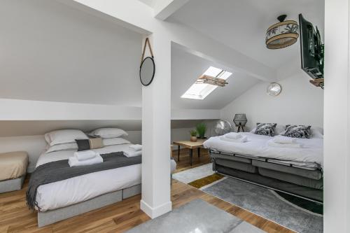 twee bedden in een slaapkamer met witte muren en houten vloeren bij MBA Splendide Appart - Banlieue Est Paris - PSB3 in Pavillons-sous-Bois