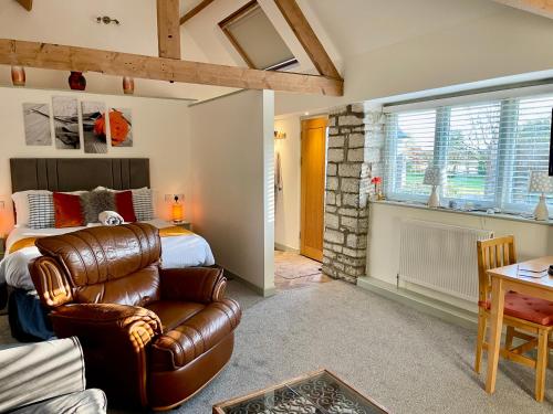 a bedroom with a bed and a leather chair at Church Farm Barn Annex in Somerton