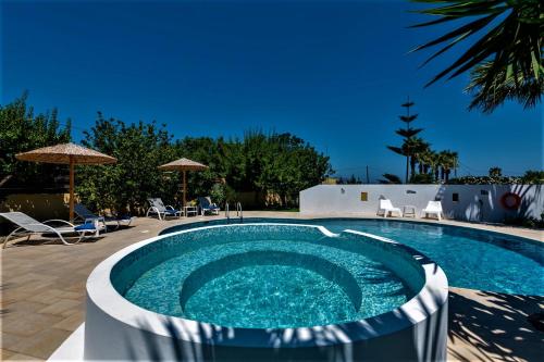 a swimming pool in a yard with chairs and umbrellas at XENOS VILLA 2 with a private pool,near the sea in Tigaki