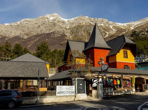 a town with a building with mountains in the background at La Villetta Food & Drink Rooms for Rent - No Reception - in LʼAquila