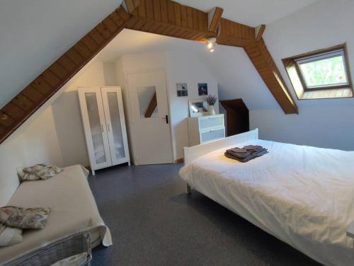 een slaapkamer met 2 bedden op een zolder bij Petite Maison cosy avec jardin, bbq, campagne in Limerzel