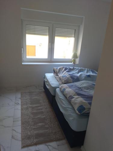 a bed in a room with a window and a rug at Ivan apartmani Posušje in Posušje