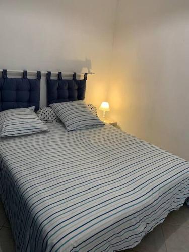 - un lit avec une couette à rayures bleue et blanche dans l'établissement Sète: Magnifique appartement 8 couchages, à Sète