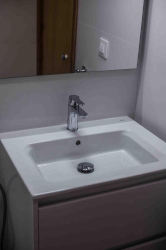 a white sink in a bathroom with a mirror at Biniplaya - Apartamento reformado al lado de la playa in Arenal d'en Castell