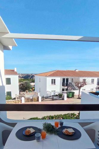 a table with two plates of food on a balcony at Biniplaya - Apartamento reformado al lado de la playa in Arenal d'en Castell