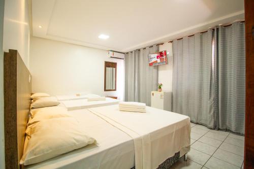 a bedroom with two beds with white sheets at Hotel Bem Brasil in Porto Seguro