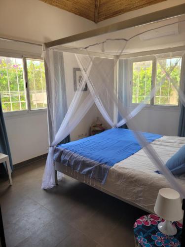 a bed with a canopy in a room with windows at Villa oasis n°5 in Gandigal