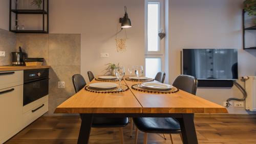 a wooden table with chairs and wine glasses on it at VacationClub - Aleja Zwycięzców Apartament 12 in Polanica-Zdrój