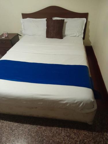 a large bed with blue and white sheets and pillows at Tim Times Ltd self contained rooms in Nairobi