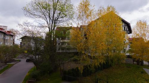 a tree with yellow leaves next to a building at VacationClub - Aleja Zwycięzców Apartament 12 in Polanica-Zdrój