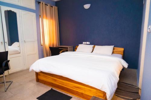 a bedroom with a large bed with a blue wall at Studio cosy et confortable in Lomé