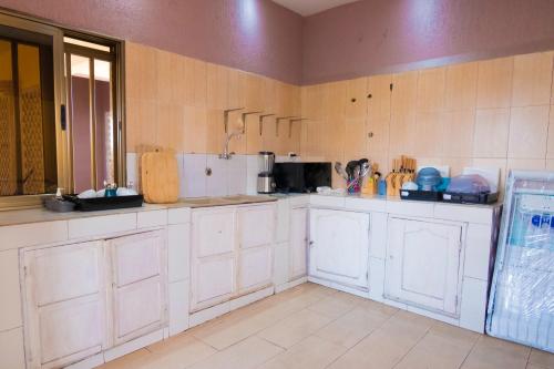 a large kitchen with white cabinets and a unintention at Studio cosy et confortable in Lomé