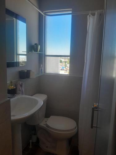 a bathroom with a toilet and a sink and a window at Casa Bosques in Cuautitlán Izcalli