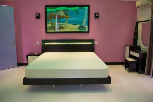 sypialnia z łóżkiem w różowej ścianie w obiekcie Le Tribord w mieście Flic-en-Flac
