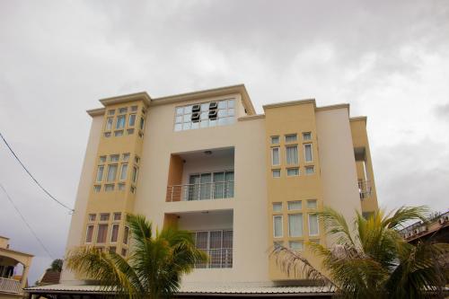 a yellow building with palm trees in front of it at Le Tribord in Flic-en-Flac