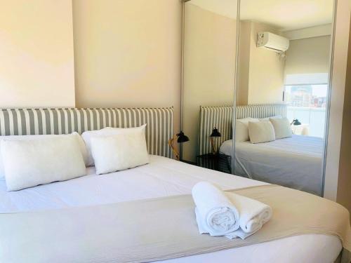 a bedroom with two beds with white pillows and a mirror at Top Rentals Belgrano in Buenos Aires