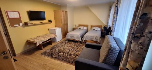 Habitación pequeña con 2 camas y sofá en Hotel Senlīči, en Jelgava