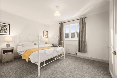 ein weißes Schlafzimmer mit einem Bett und einem Fenster in der Unterkunft Cotswolds Retreat - Little Corders 