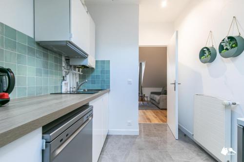 une cuisine avec des placards blancs et du carrelage bleu dans l'établissement MBA Splendide Appart - Wilson 2 - Mairie de Montreuil, à Montreuil