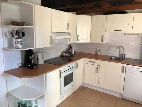 eine Küche mit weißen Schränken und einem Waschbecken in der Unterkunft Longère chaleureuse et familiale - 3 chambres in Limerzel