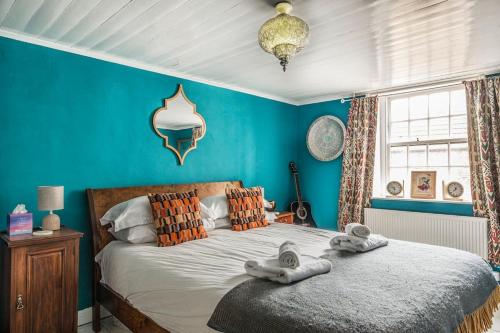 a bedroom with a large bed with blue walls at The Old Post Office - Truly unique, quirky house in Kent