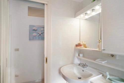 La salle de bains blanche est pourvue d'un lavabo et d'un miroir. dans l'établissement Gli Orti sul mare 1, à Bordighera