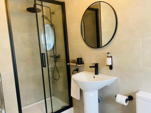 a bathroom with a sink and a shower with a mirror at The Punchbowl Lapworth in Solihull