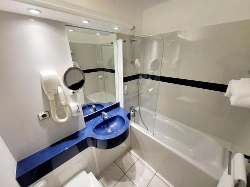 La salle de bains est pourvue d'un lavabo bleu et d'une douche. dans l'établissement Citotel Hôtel Le Capricorne, à Marmande