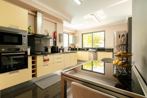 a large kitchen with a table and a counter top at Villa Nunes, Big Holiday house with private pool in Calheta